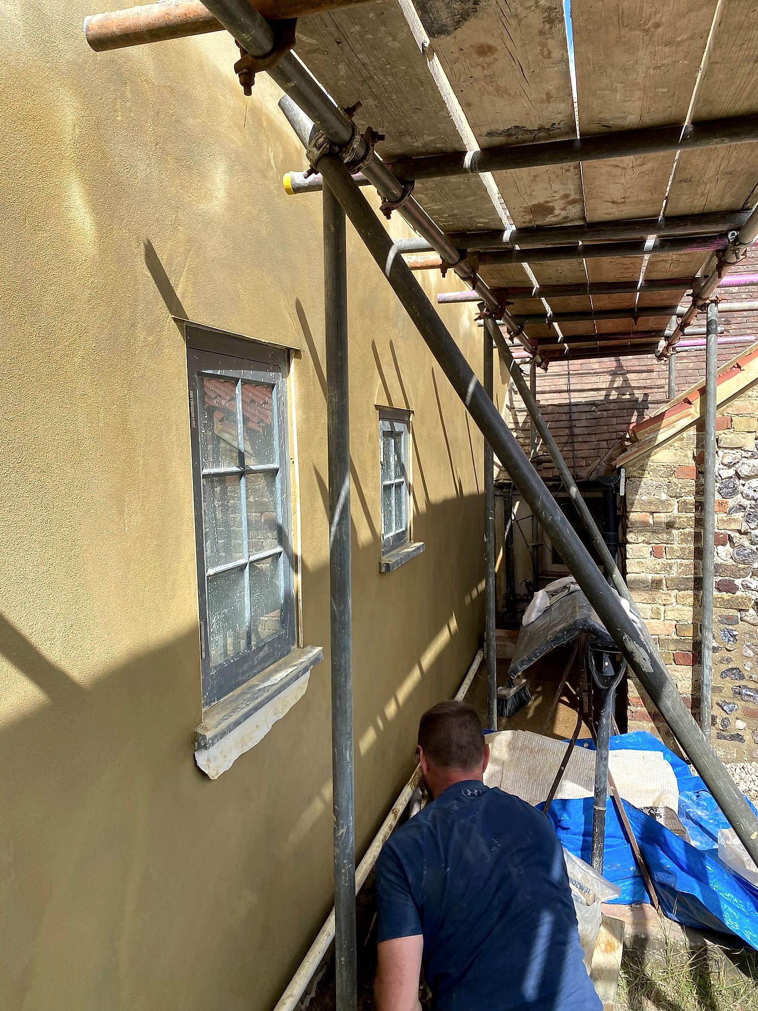 Lee Wehrle applying sand and cement render to a period property exterior from scaffolding in East Kent