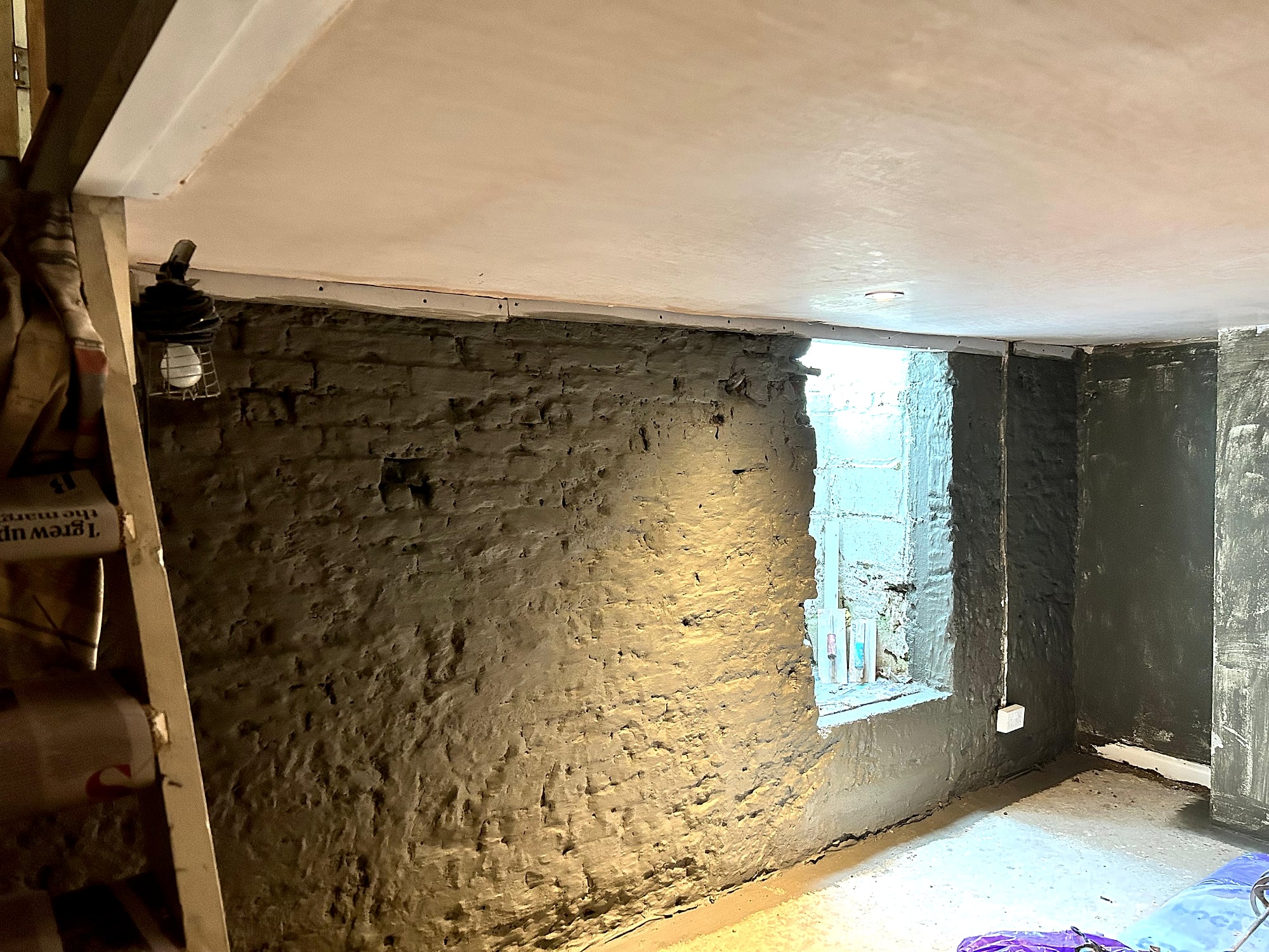 Basement with freshly plastered ceiling and damp-proofed walls showing staircase in Kent cellar conversion