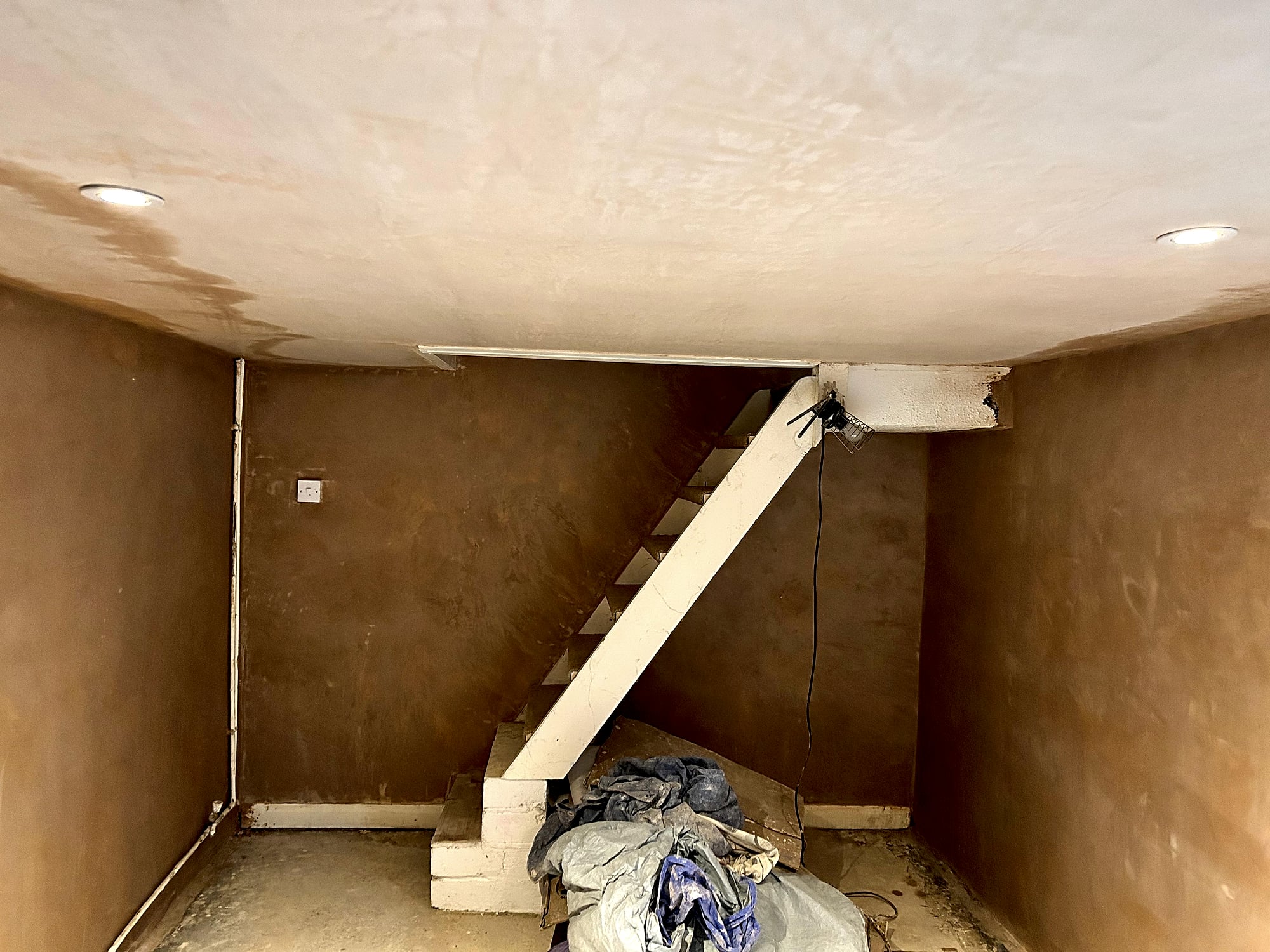 Freshly plastered basement walls and ceiling with recessed spotlights and staircase in East Kent cellar conversion