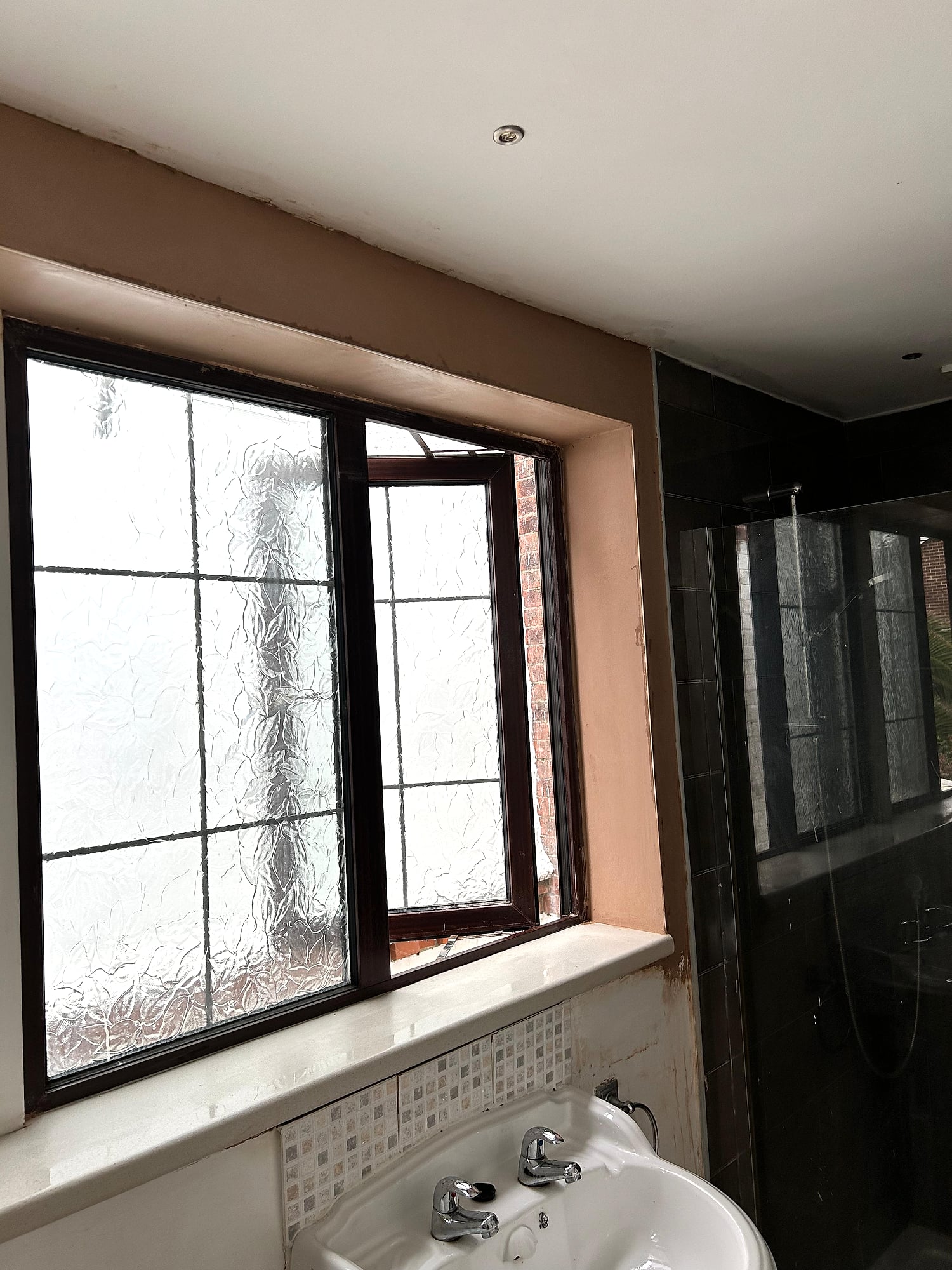 Bathroom window reveal freshly plastered with frosted glass window and shower screen in Kent home