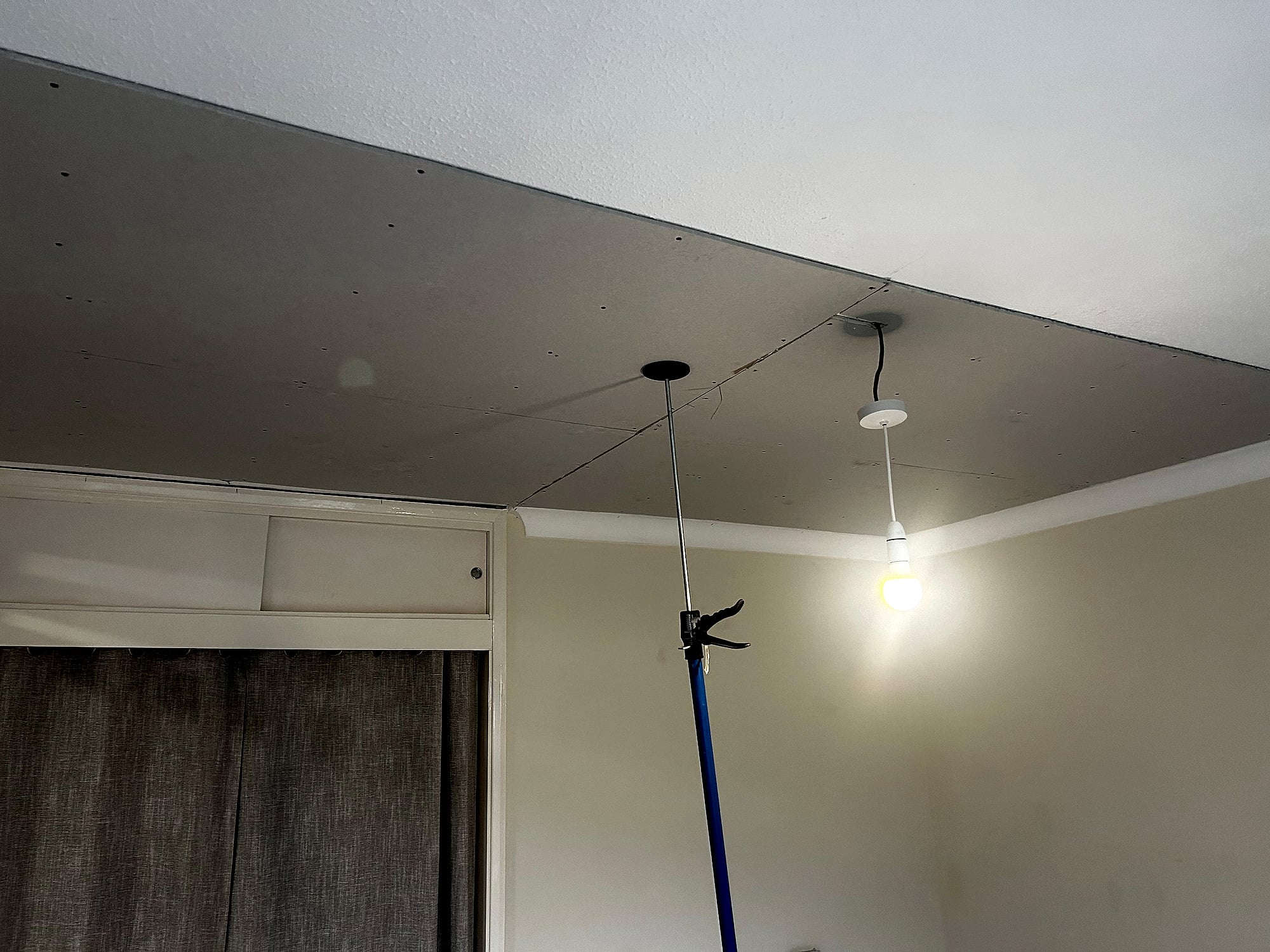 Bedroom with new lowered plasterboard ceiling fitted above curtain rail showing neat finish in Kent home