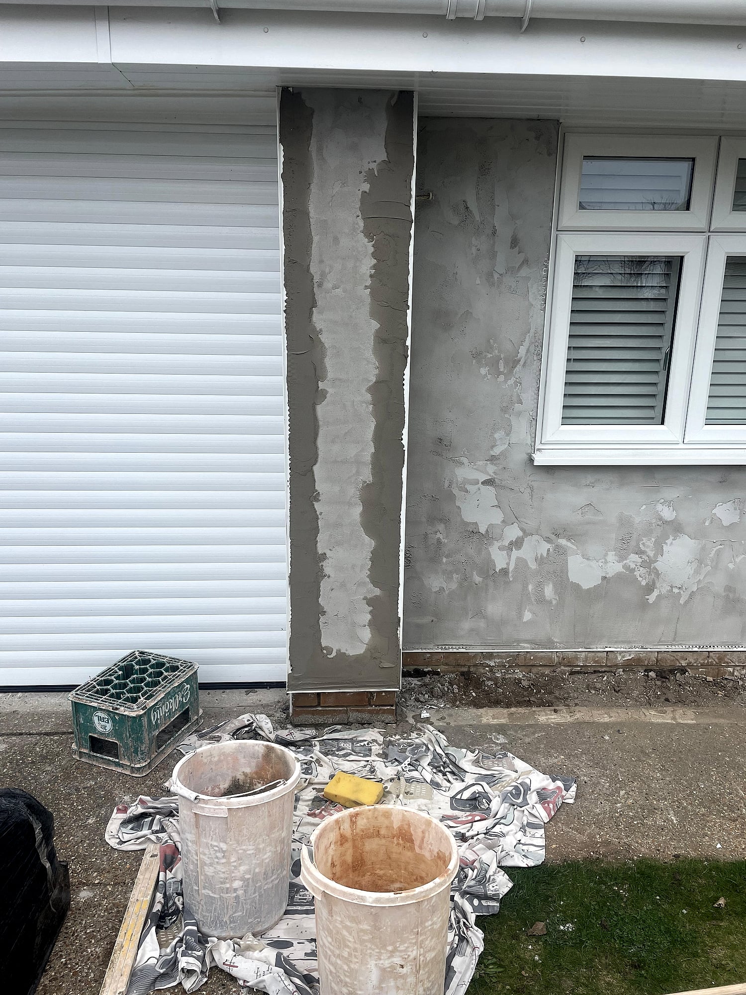 Bungalow exterior render in progress with plastering tools and mixing buckets on driveway in East Kent