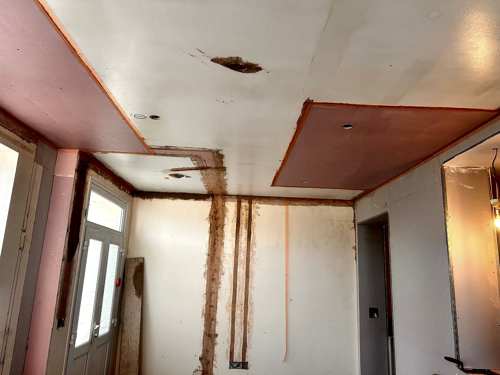 Ceiling partially skimmed over plasterboard showing progression of skim coat with spotlights in Kent extension