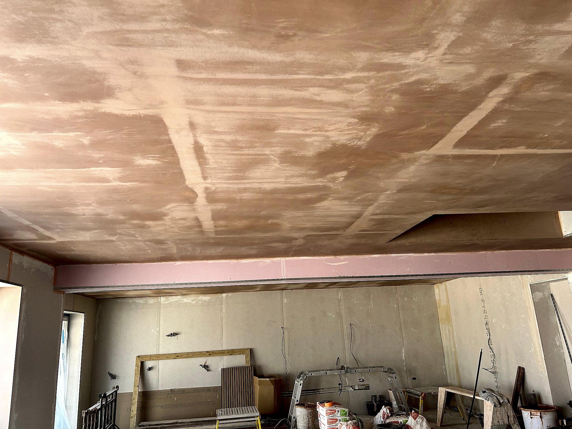 Room with freshly plastered ceiling drying showing beam detail and plasterboard below in Kent renovation