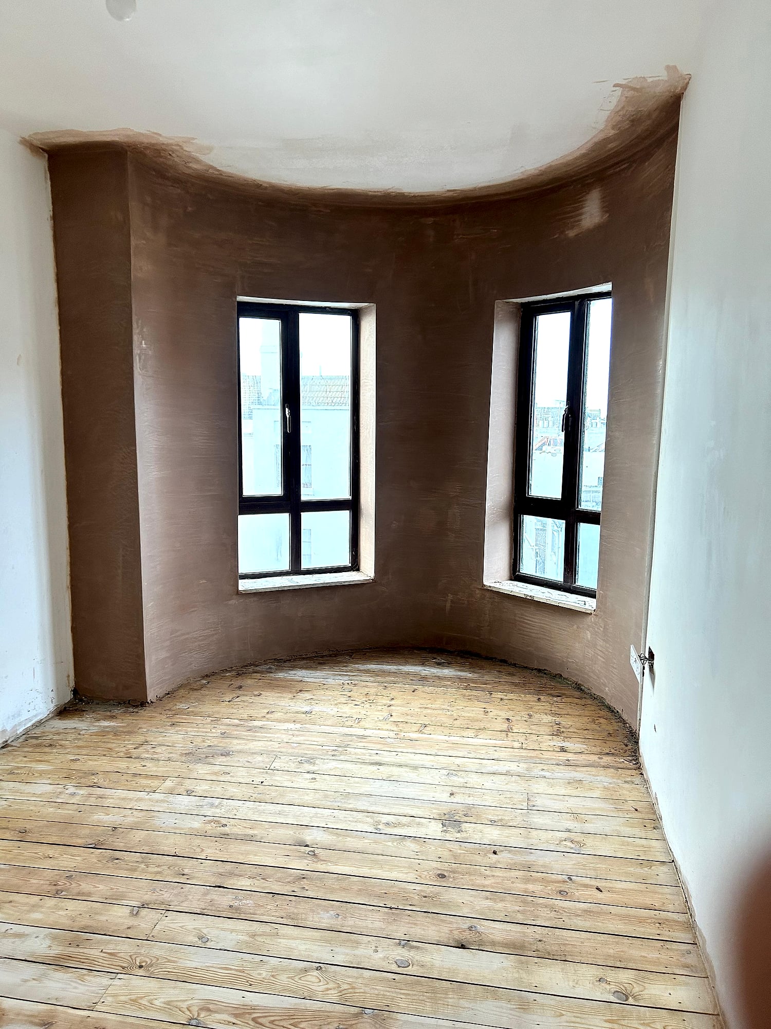 Curved bay window walls freshly plastered with smooth skim coat showing original floorboards in East Kent property