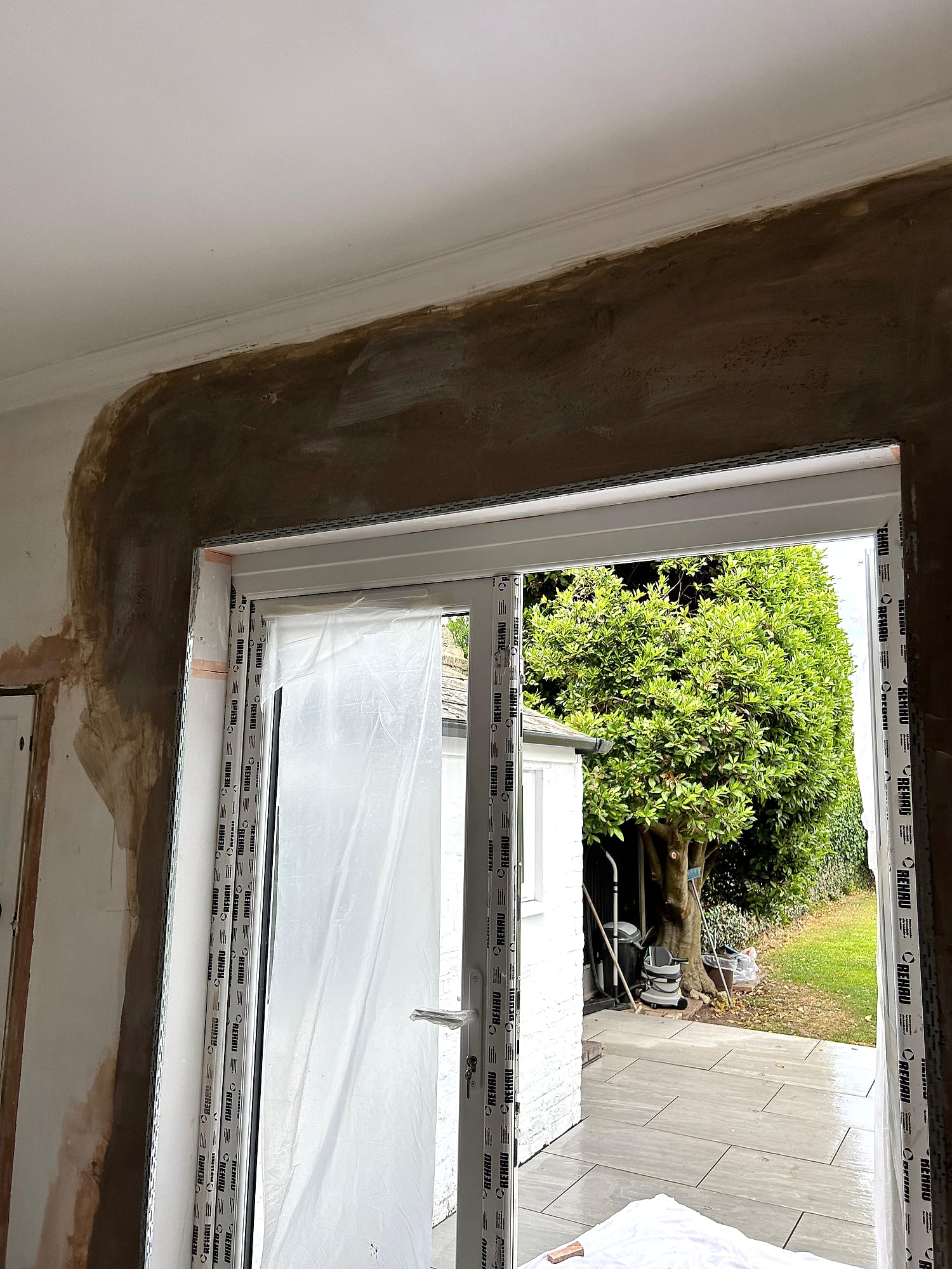 French door reveal with fresh brown coat plaster being applied around new patio door frame in Kent home