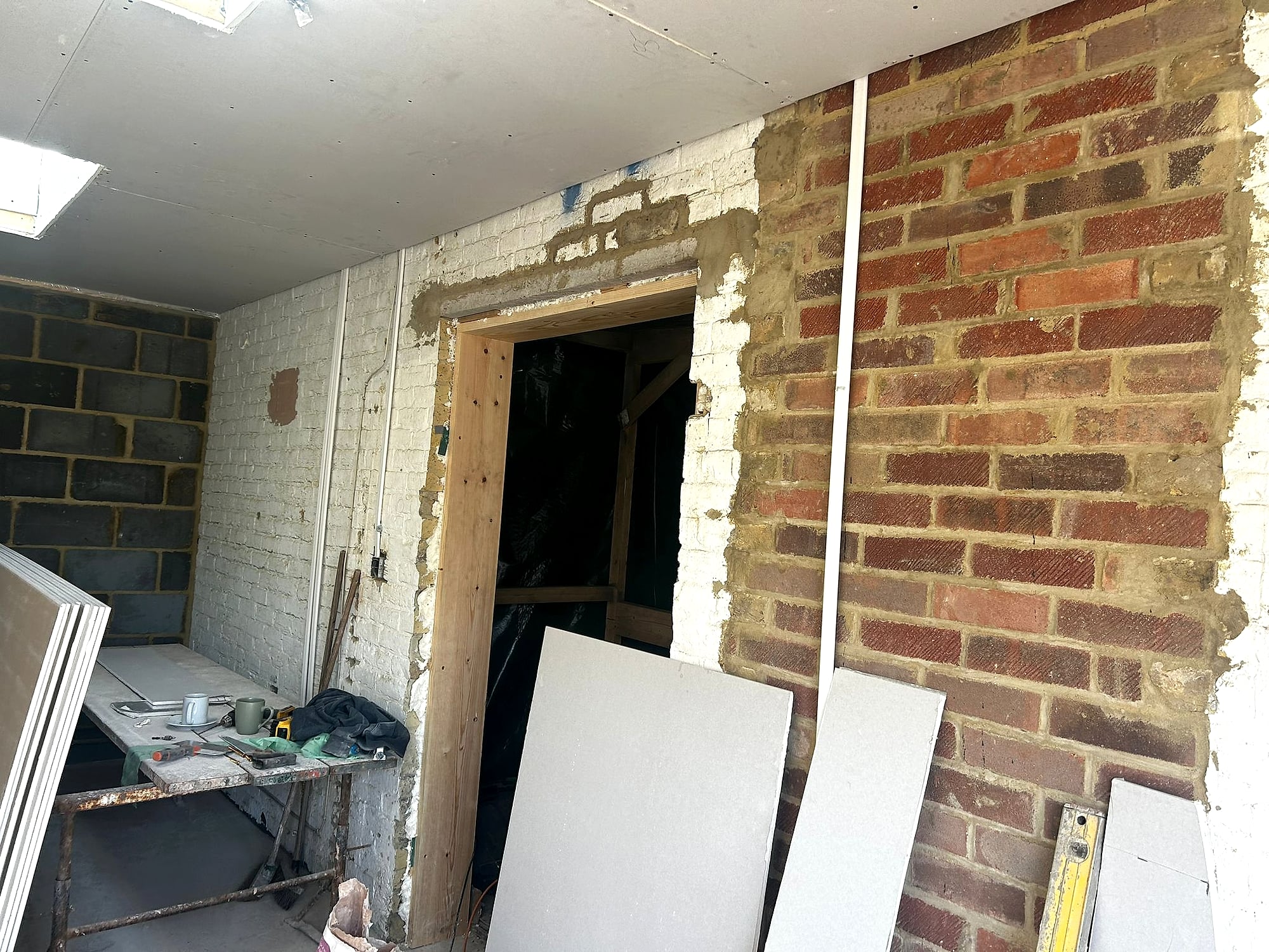 Extension doorway with exposed brickwork and plasterboard sheets ready for dry lining in Kent renovation