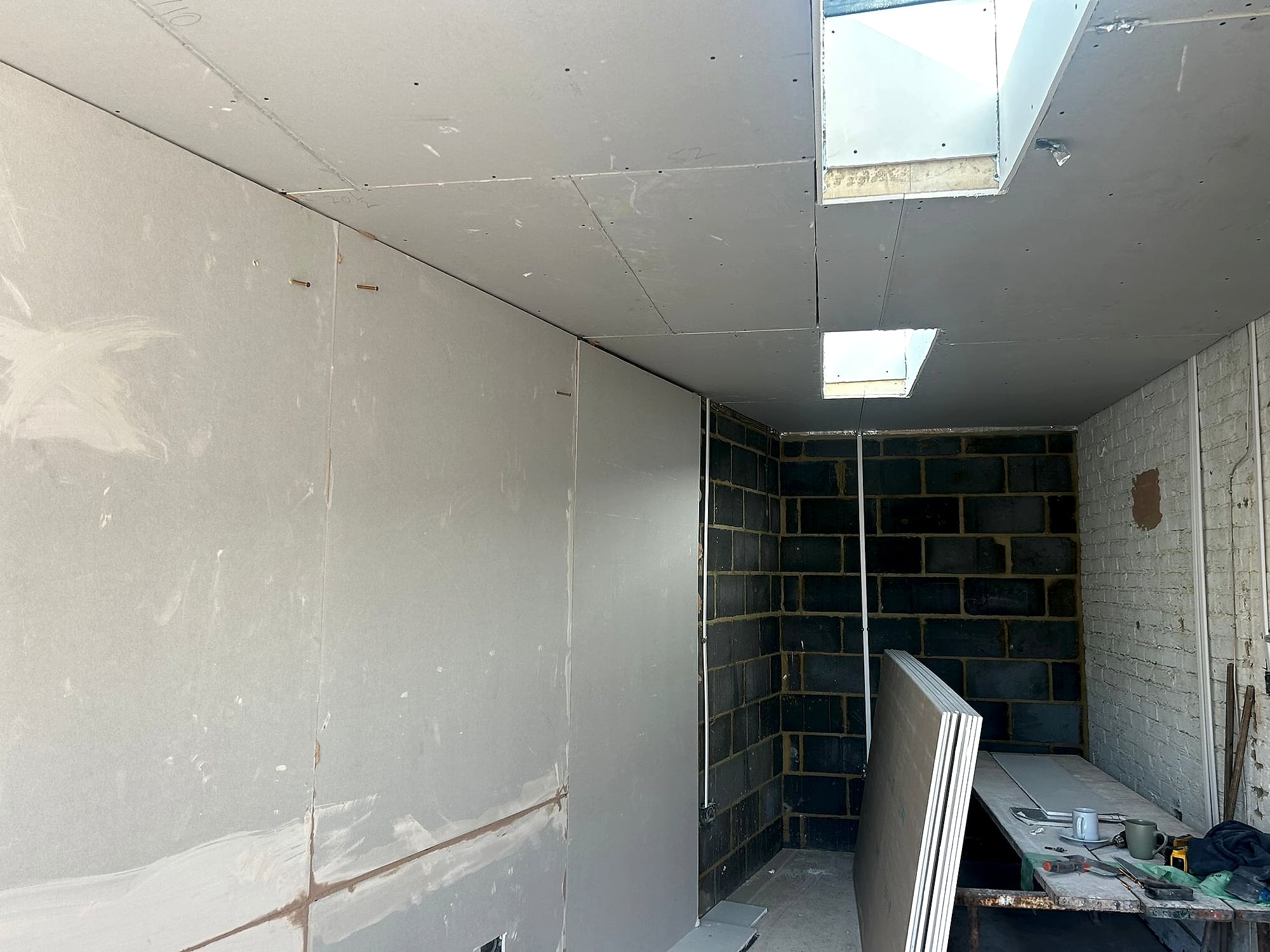 Plasterboard ceiling and walls fitted in blockwork extension with skylights ready for plastering in Kent