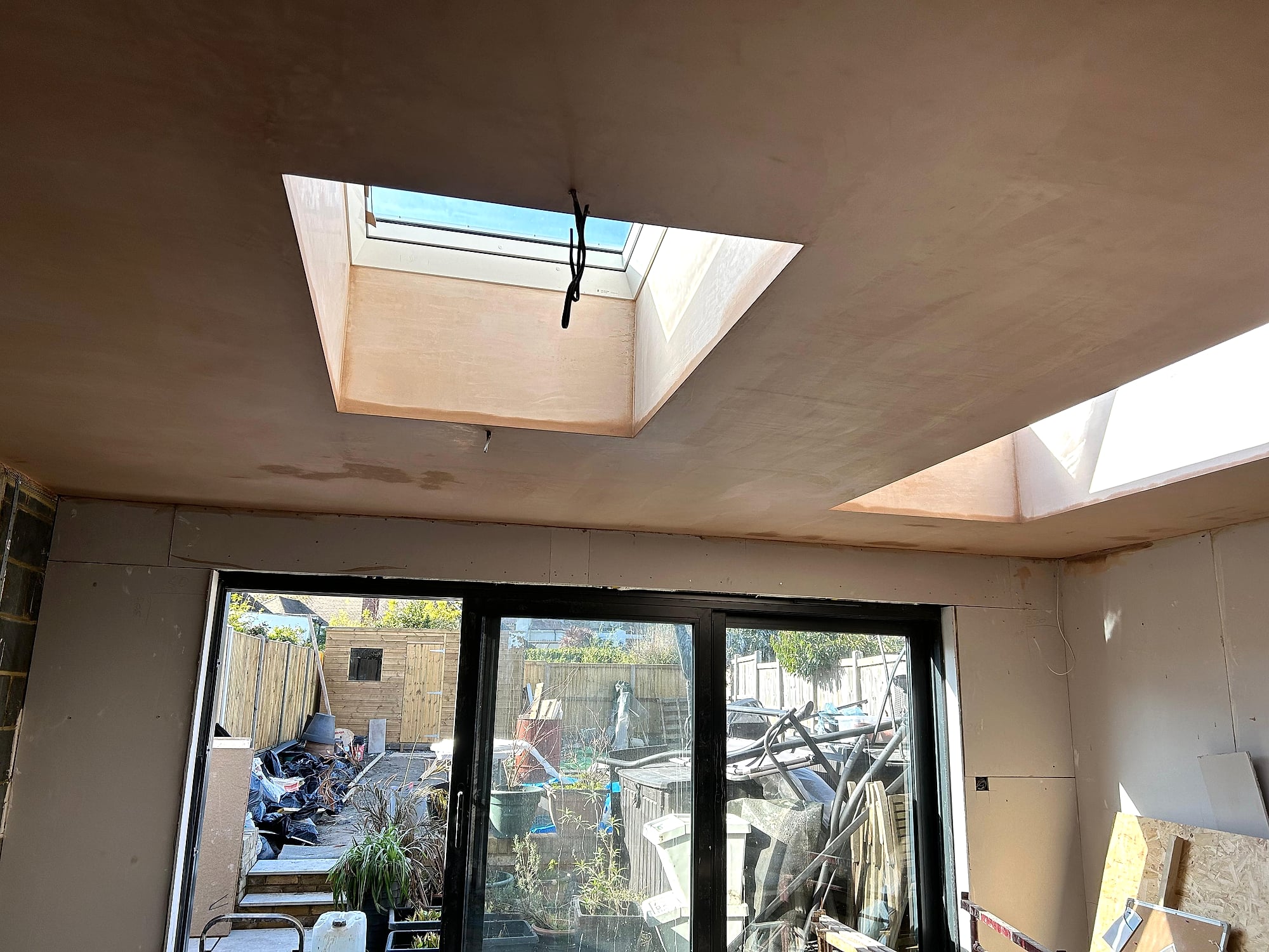 Kitchen extension ceiling freshly plastered with skylight reveals and bifold doors in Kent home