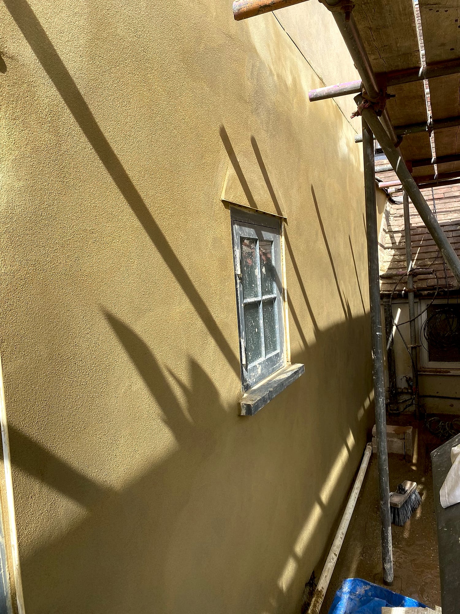 Sand and cement render applied to period property exterior wall viewed from scaffolding in Kent