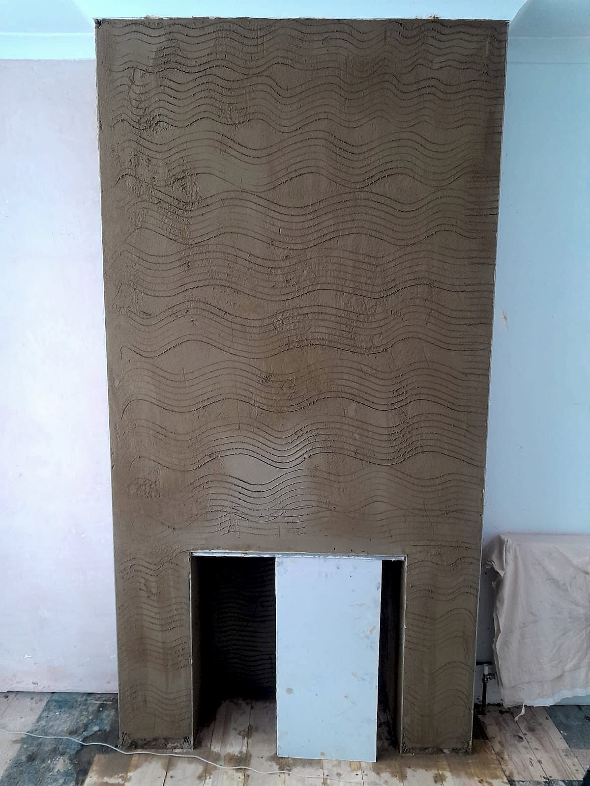 Fireplace breast with adhesive scratch coat ready for tiling showing wave pattern keying in Kent home