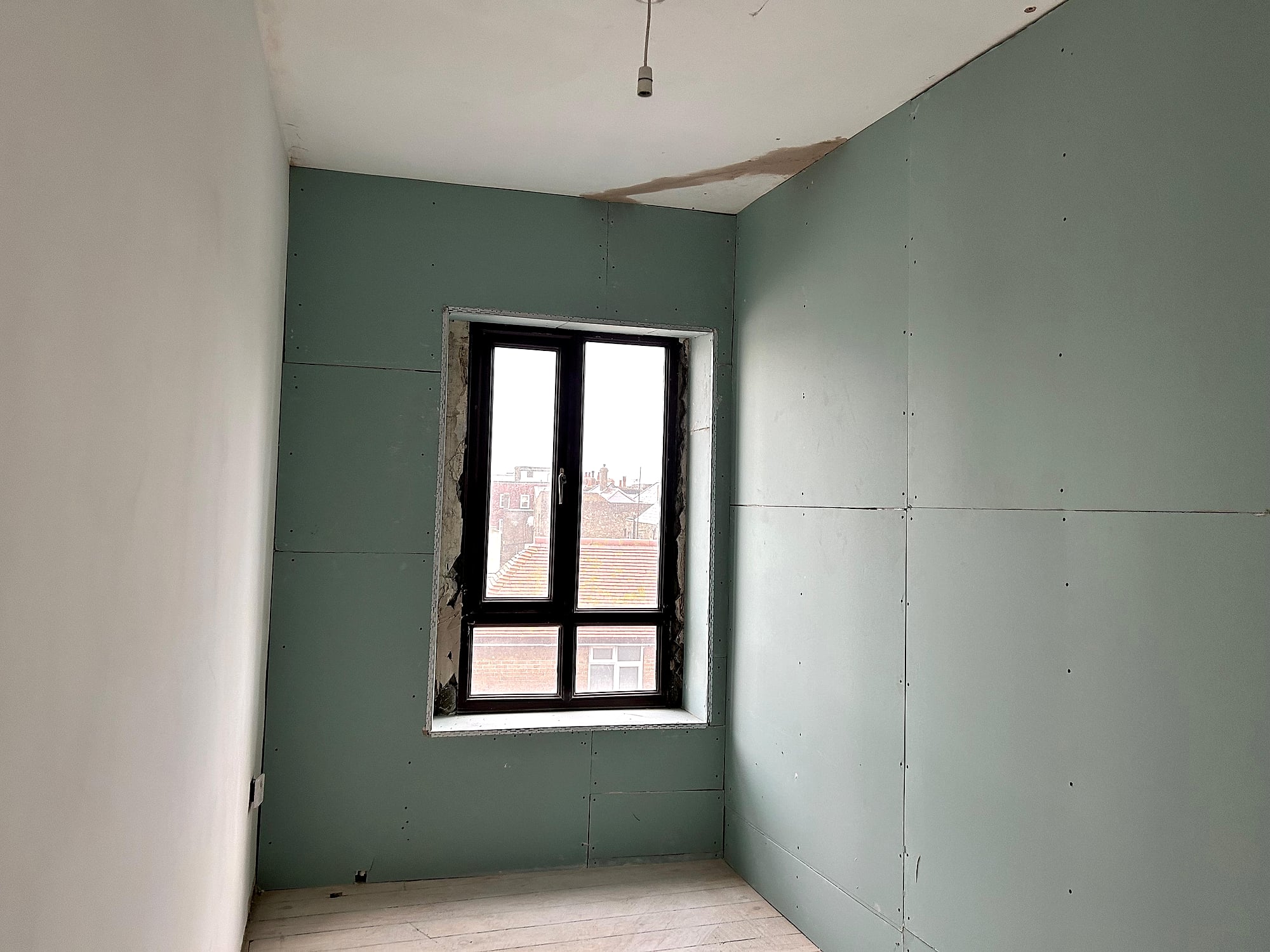 Moisture-resistant plasterboard dry lining fitted around window in period property renovation in East Kent