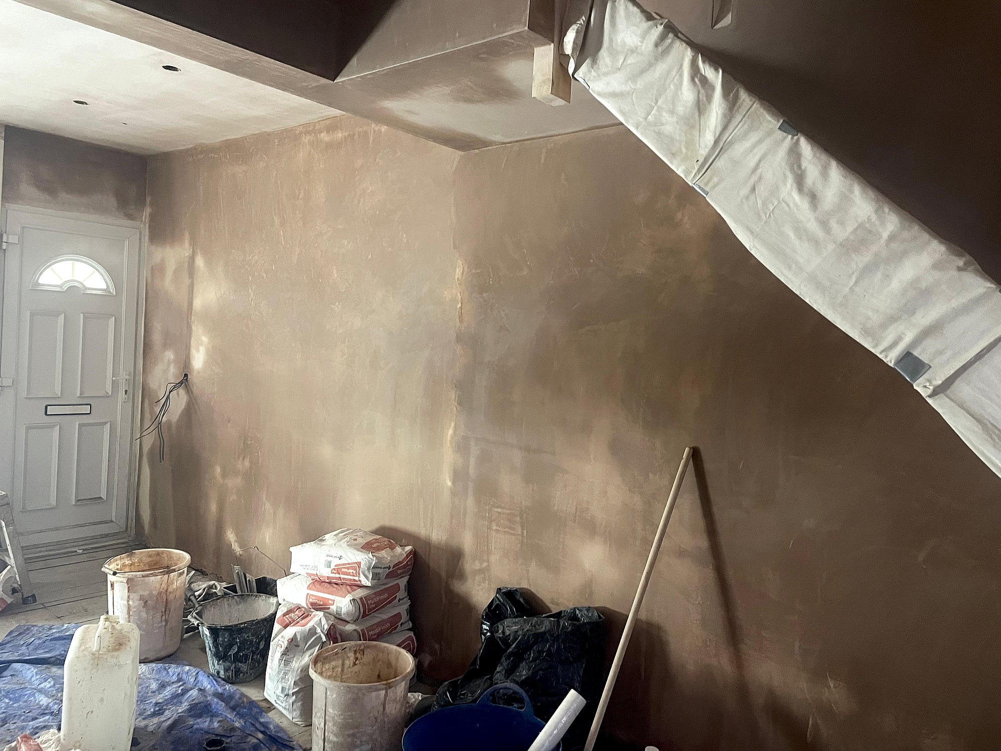 Hallway and stairwell freshly plastered with plaster bags and dust sheeting during renovation in Kent home
