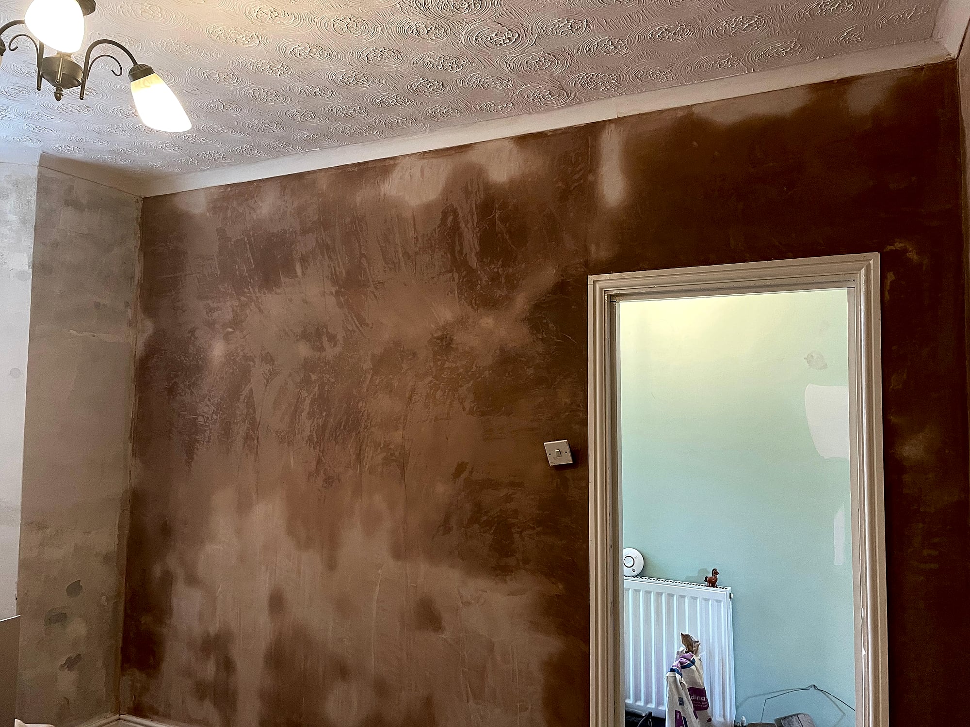 Hallway walls being re-plastered with fresh wet skim coat next to textured ceiling in Kent period home