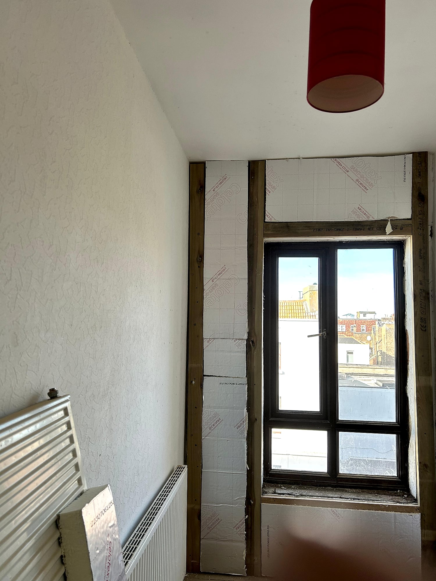 Celotex insulation fitted between timber stud framing around window before plasterboarding in Kent renovation
