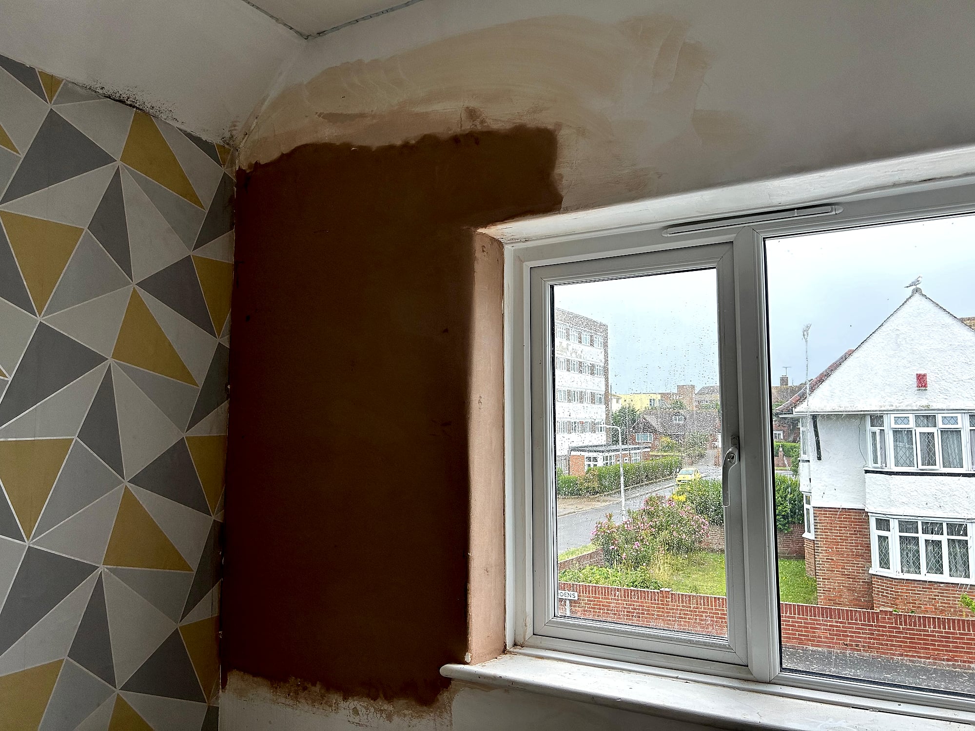 New doorway opening plastered into kitchen wall with fresh render showing garden patio in Kent home