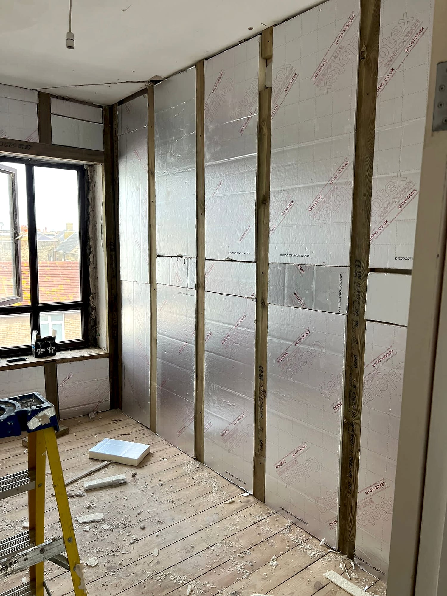 Plasterer applying skim coat to curved bay window from rear view showing tools and equipment in Broadstairs