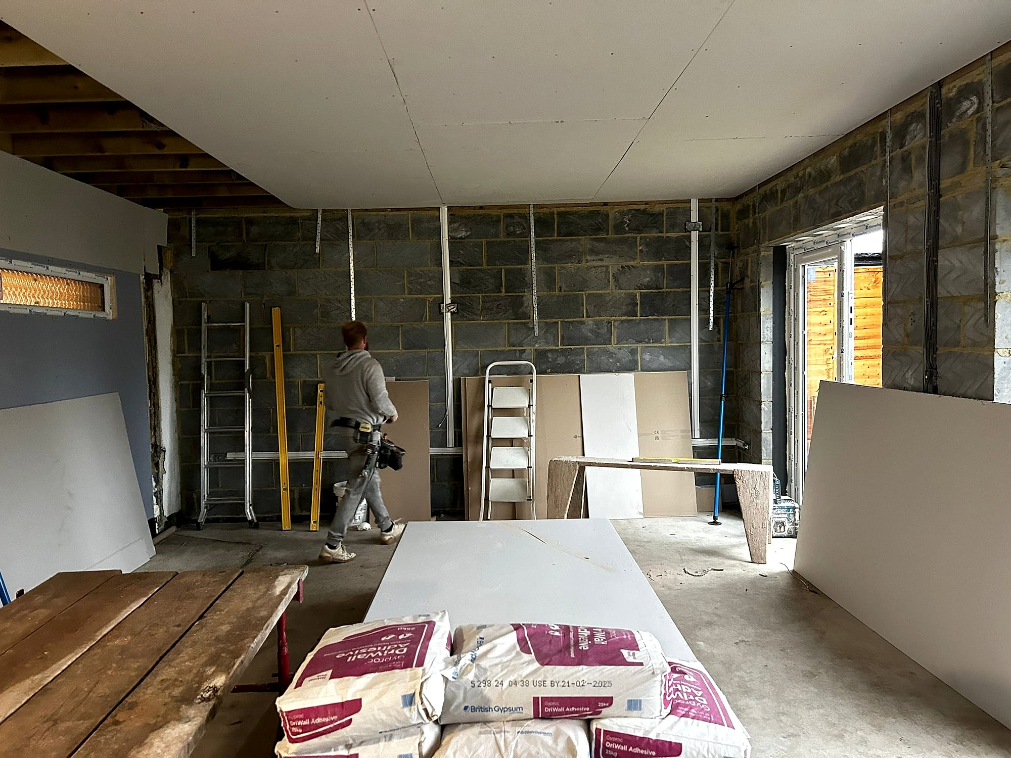 Extension dry lining in progress with plasterboard sheets and plaster bags on scaffold boards in Kent