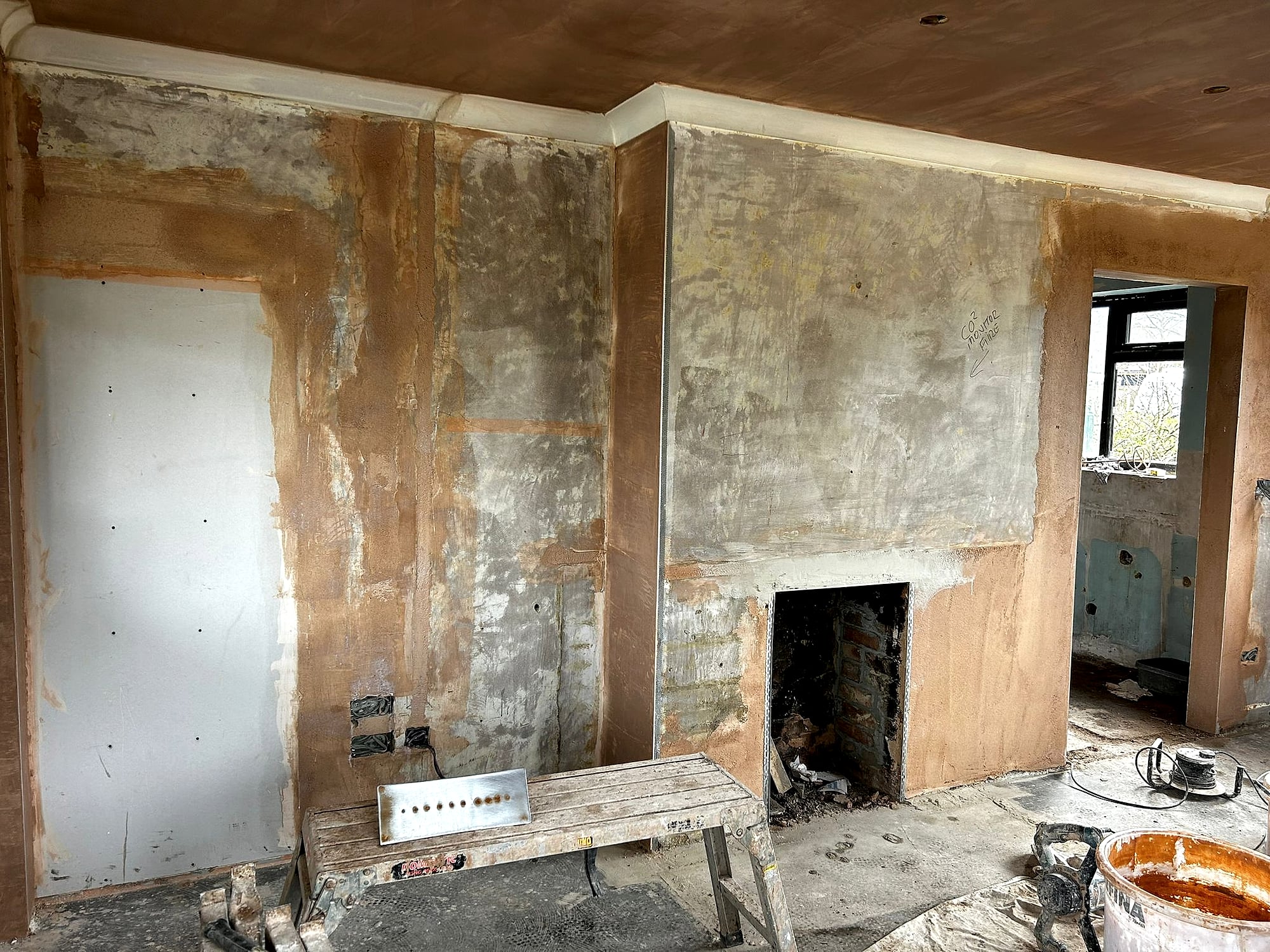 Living room walls being skimmed around fireplace breast showing fresh plaster and boarding in Kent renovation