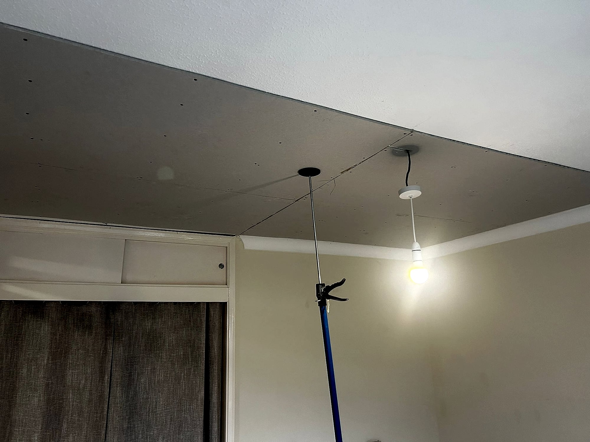 New plasterboard lowered ceiling fitted in bedroom with curtain pelmet and doorway in Kent property
