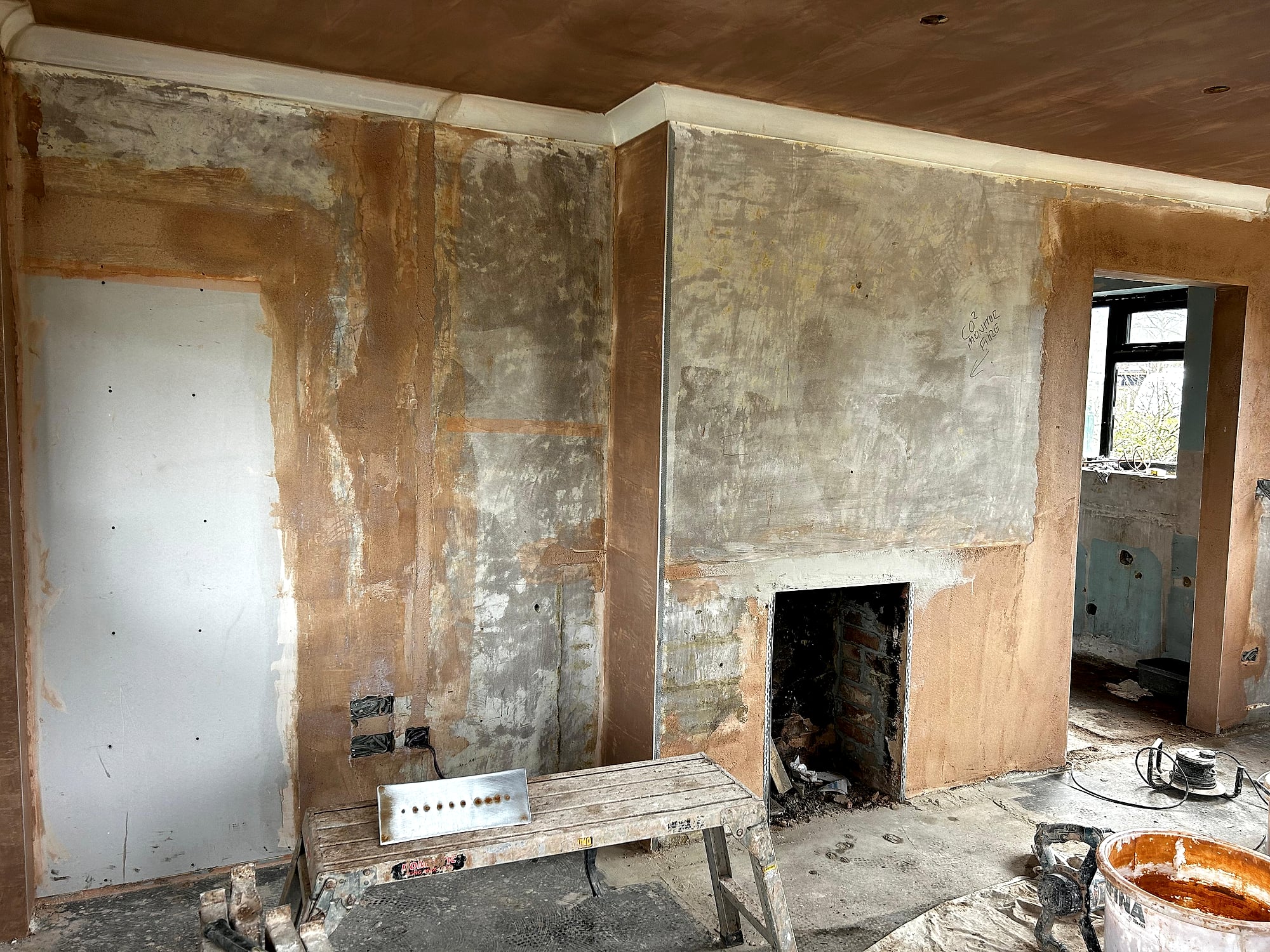 New build room with fresh skim coat on ceiling showing fireplace wall with plasterboard patches in Kent home