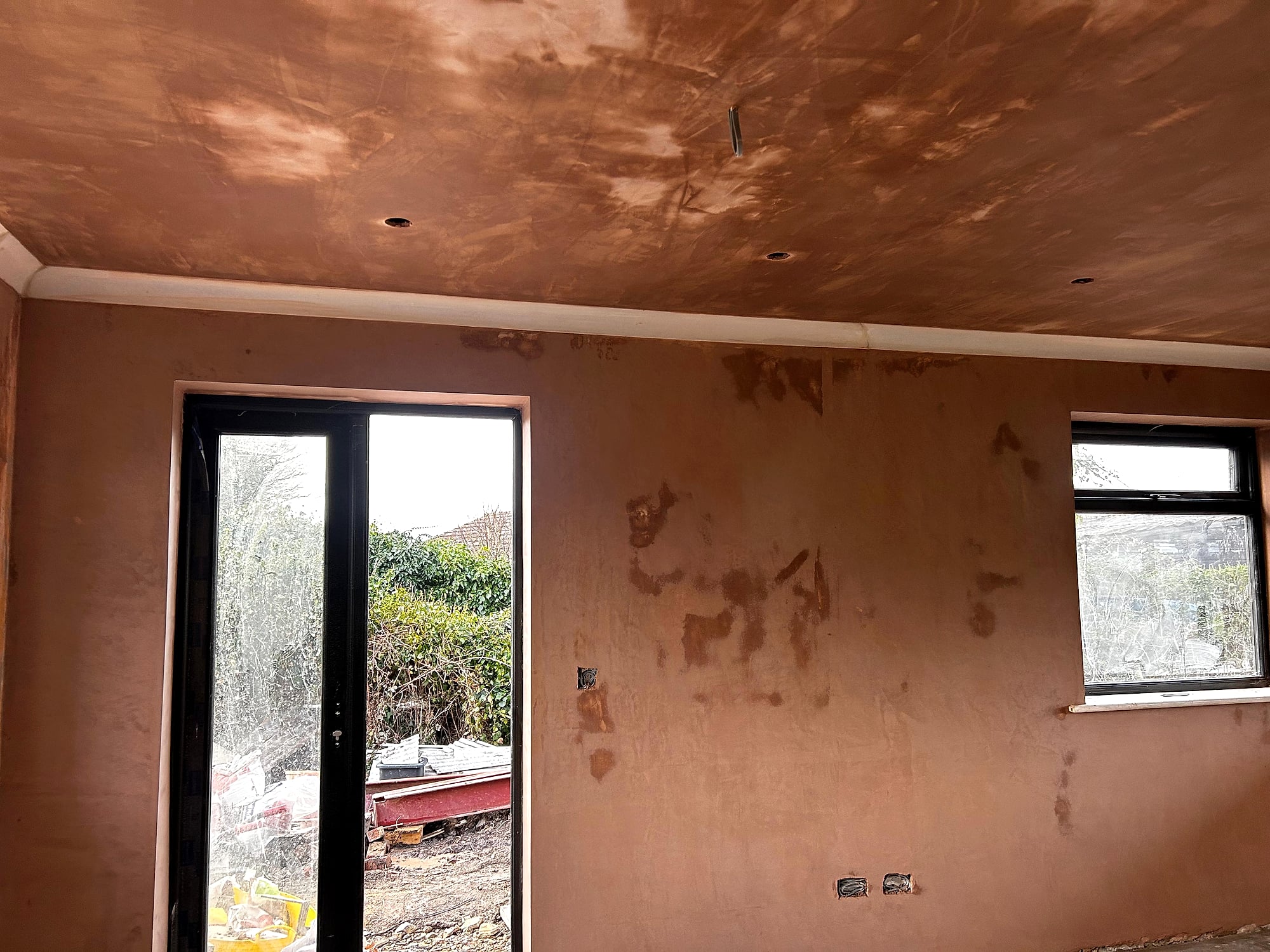 New build room with fresh skim coat on walls and ceiling showing garden door and black frame windows in Kent