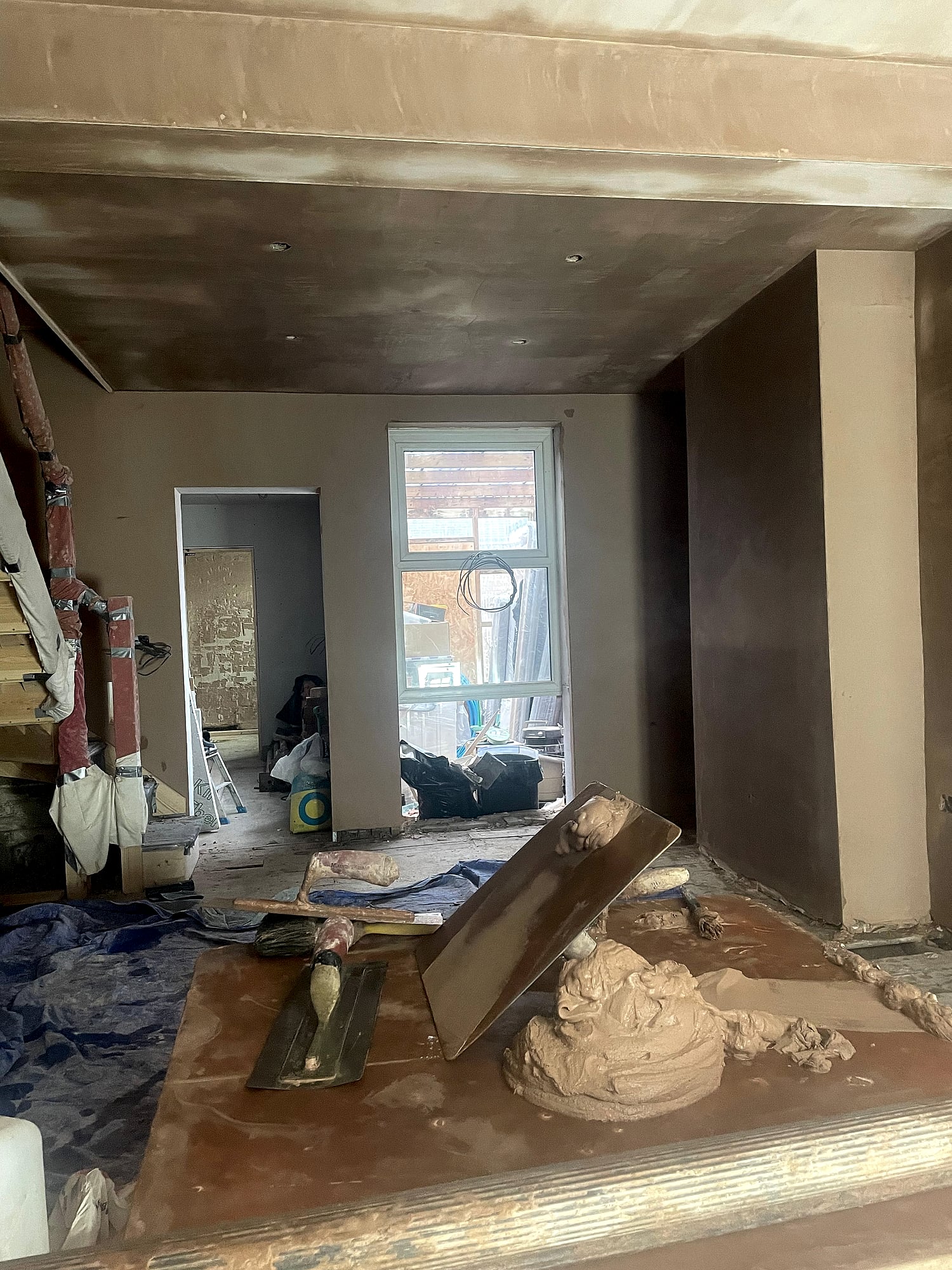 Open plan room with fresh plaster on walls and ceiling showing patio doors and garden view in Kent property