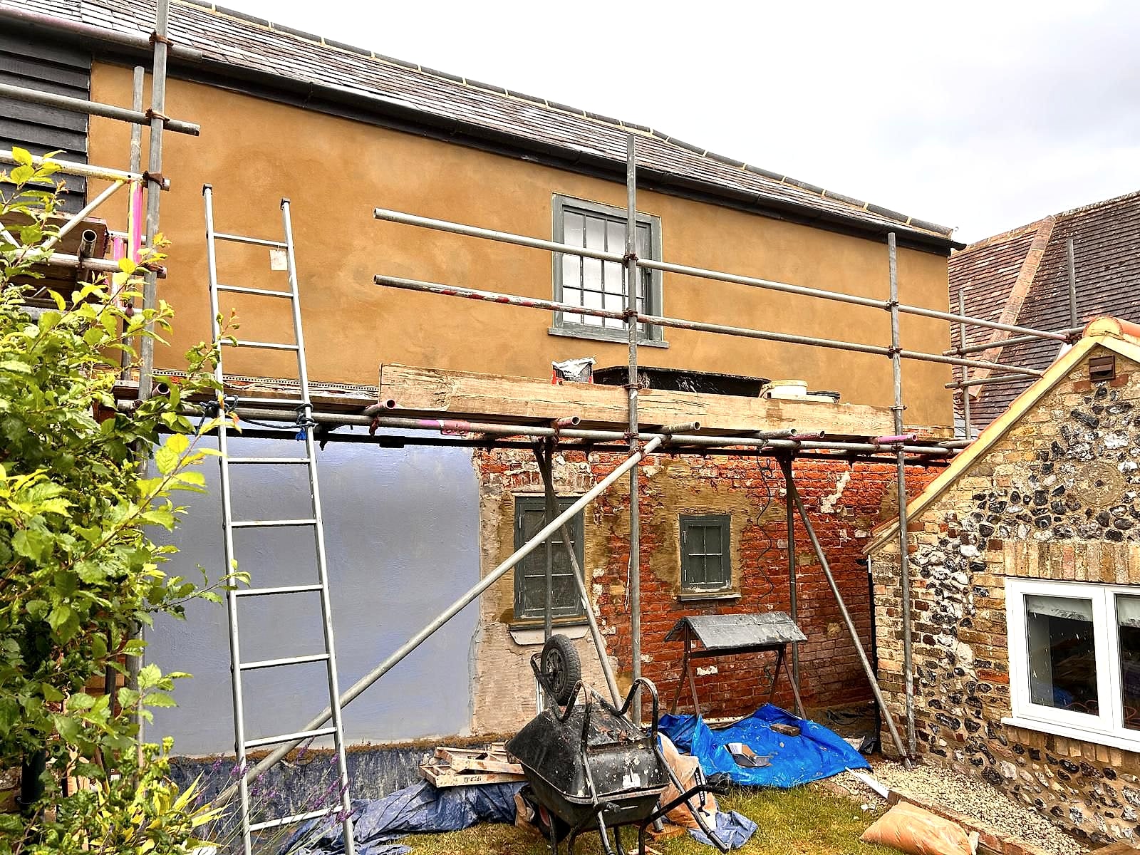 Period property rendering in progress showing fresh render above exposed brick base with scaffolding in Kent