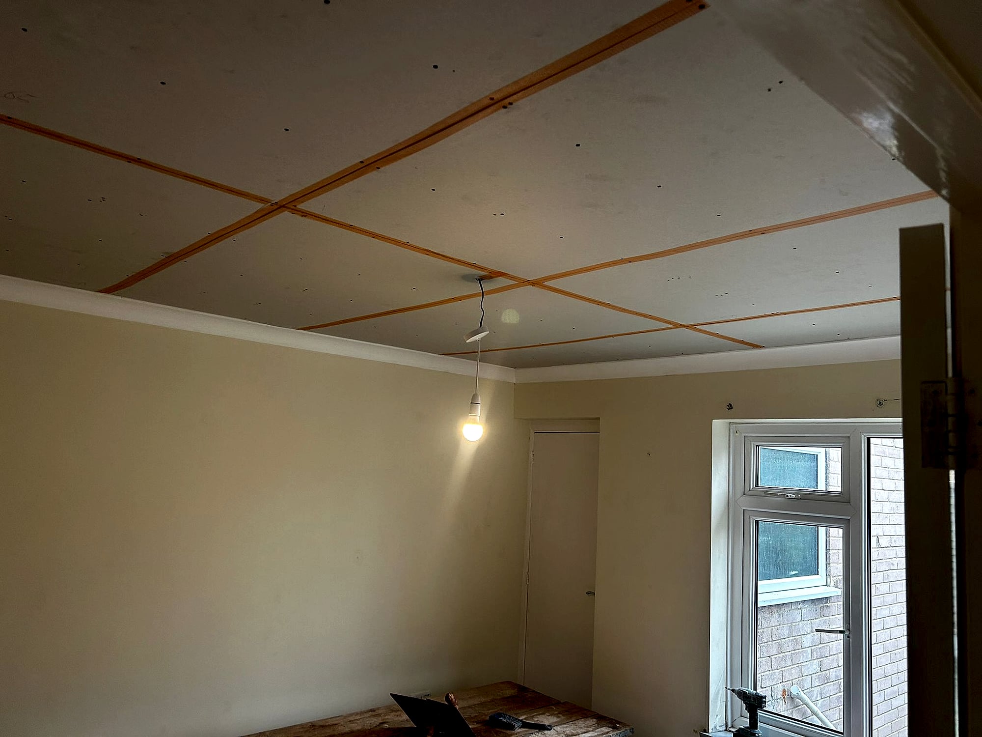 New plasterboard ceiling with taped joints ready for skimming in room with patio door in Kent home