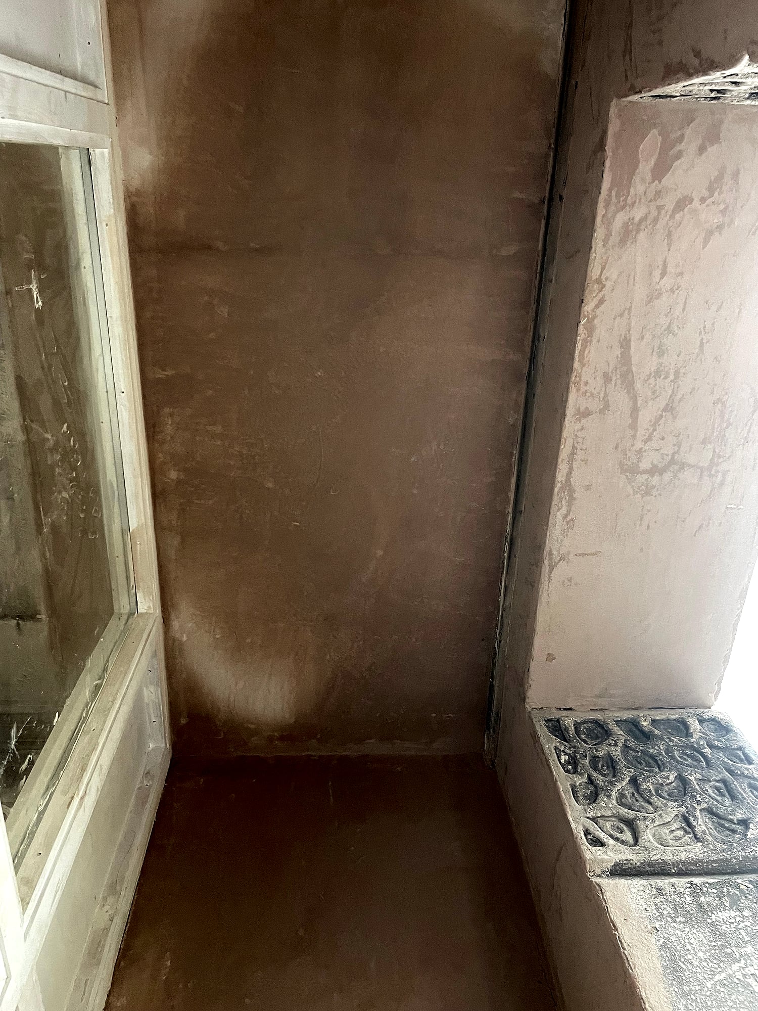 Freshly plastered porch walls meeting ornamental Victorian tiles on period property entrance in East Kent