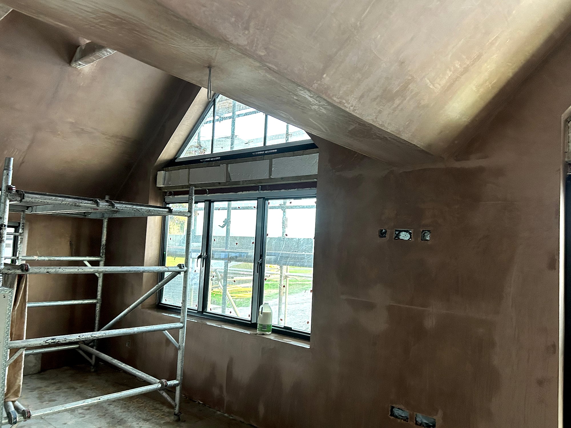 Vaulted ceiling plastering with scaffolding beside apex window and bifold doors in Kent new build extension