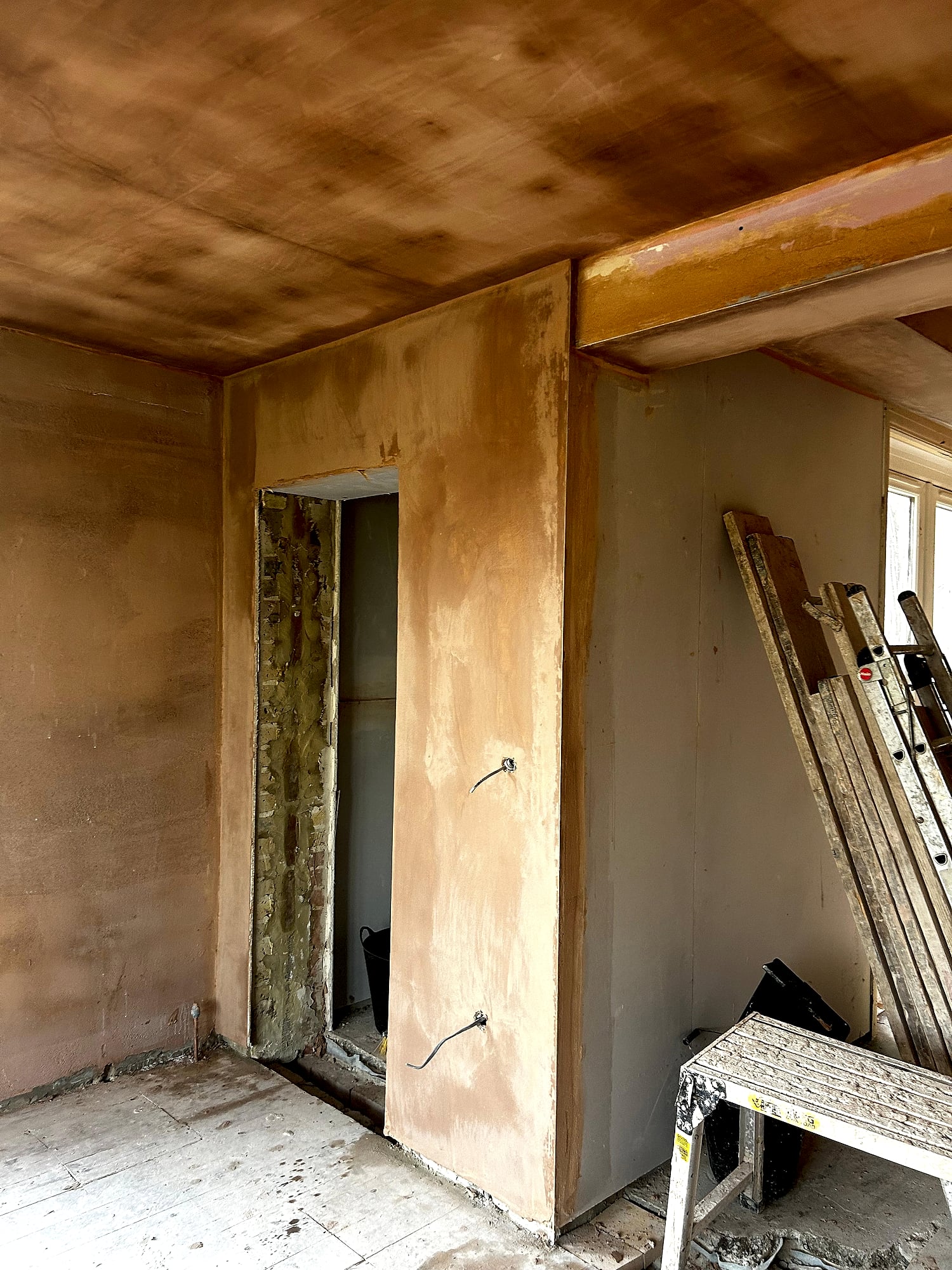 Victorian house room with fresh plaster showing partition wall and doorway to unfinished area in Kent