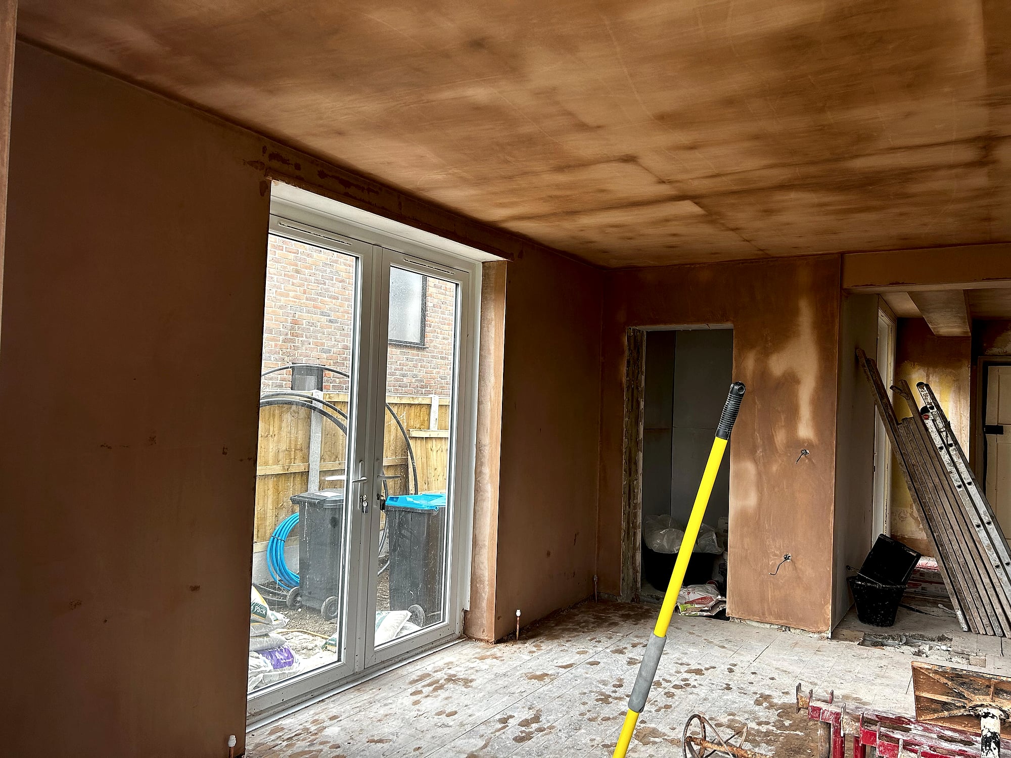 Victorian house room with fresh skim coat on walls and bay window with garden view during renovation in Kent